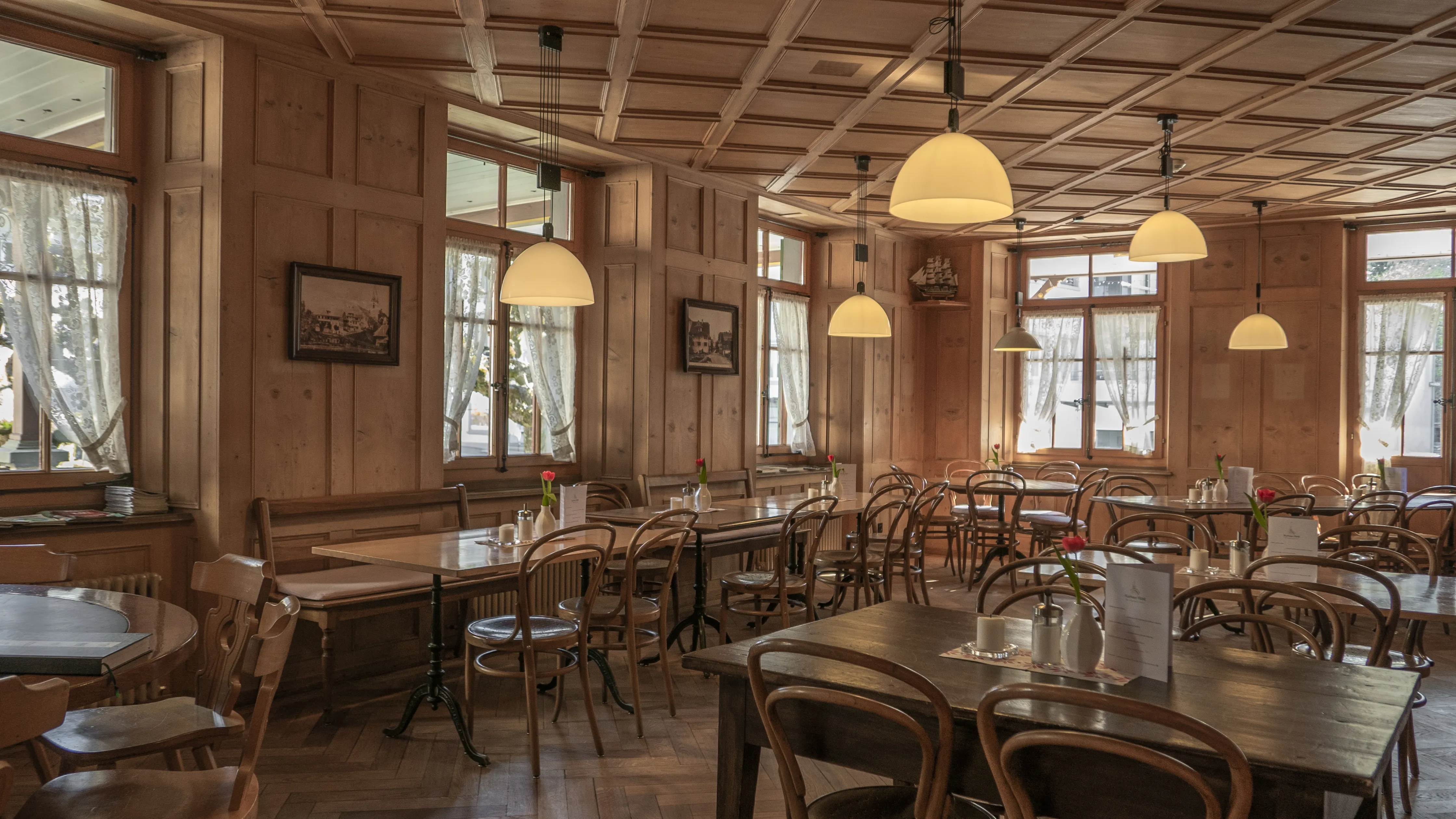 The roastery dining room, timber panelling and pendant lamps over bentwood chairs
